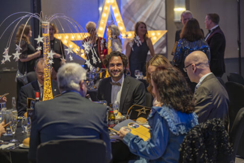 people seated around a table smile at one another