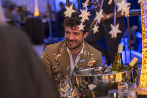 a man smiling at his companions around the table