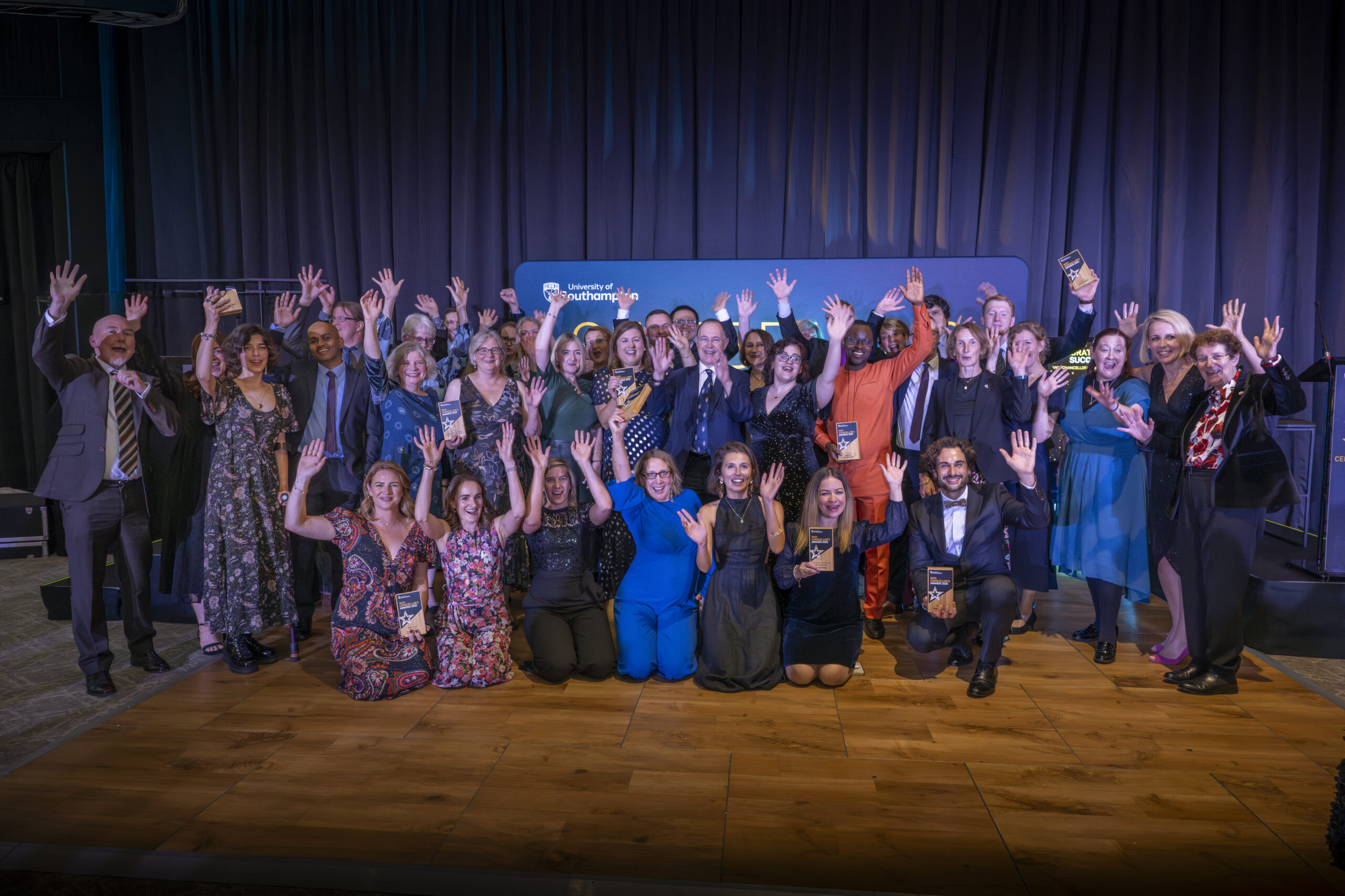 A large group of people smiling and waving at the camera.
