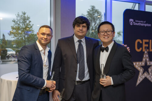 three people in formal attire smile at the camera