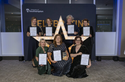 A group of people kneeling and standing around a large star, holding certificates and smiling at the camera.