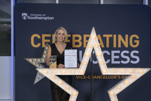 A person standing behind a large star, holding a certificate and smiling at the camera.