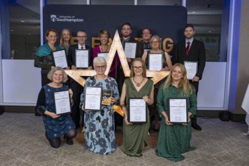 A group of people kneeling and standing around a large star, holding certificates and smiling at the camera.