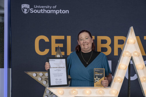 A person standing behind a large star, holding a certificate and smiling at the camera.