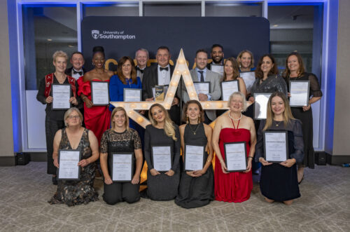 A large group of people kneeling and standing around a large star, holding certificates and smiling at the camera.