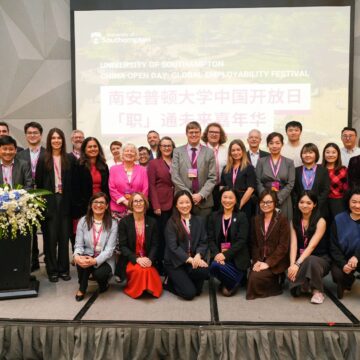 A large, smiley group of people wearing pink lanyards.