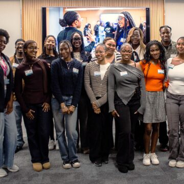 A group of young people, wearing name badges, are stood together and posing for a photo.