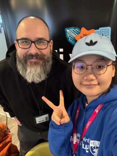 Staff member and Student Ambassador showing a 'peace' sign smiling at the camera