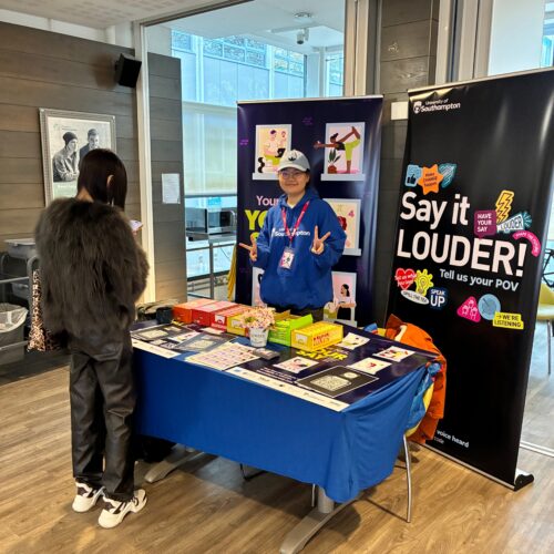 Student Ambassador near their NSS stand smiling at the camera