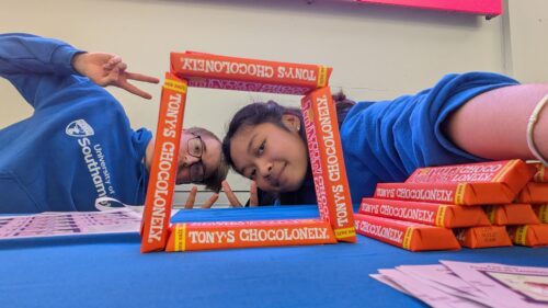 Student Ambassadors posing for the camera looking through a figure made of chocolates