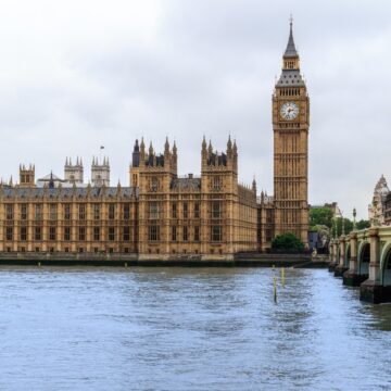 The Houses of Parliament with a bridge to the right and water in front.