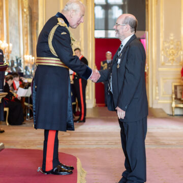 Professor John Marshall shaking hands with King Charles III.